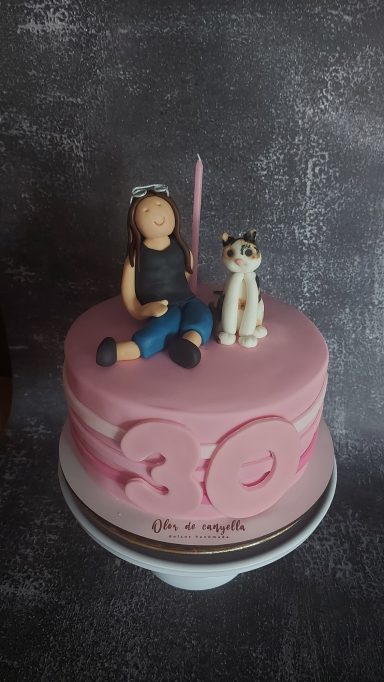 Tarta rosa decorada con una figura de niña y un perro de cerámica.
